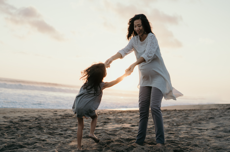 young-beautiful-pregnant-woman-with-her-little-cute-daughter-playing-in-the-beach