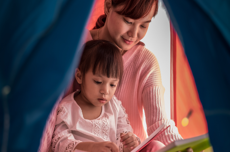 asian-mother-and-child-daughter-with-book-and-flashlight-before-going-to-bed