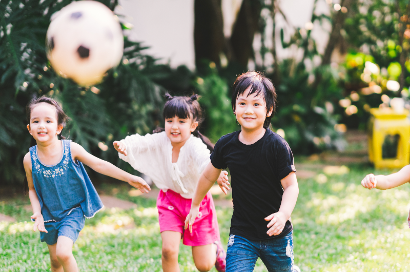 asian-and-mixed-race-happy-young-kids-running-playing-football-together-in-garden-multi-ethnic-child